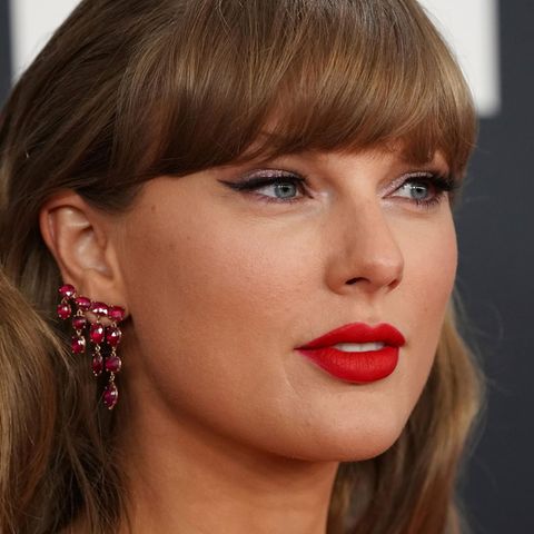 Taylor Swift posiert auf einem Roten Teppich und lächelt leicht