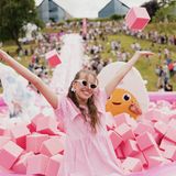 Frau steht lachend in einem pinkfarbenen Spielebecken