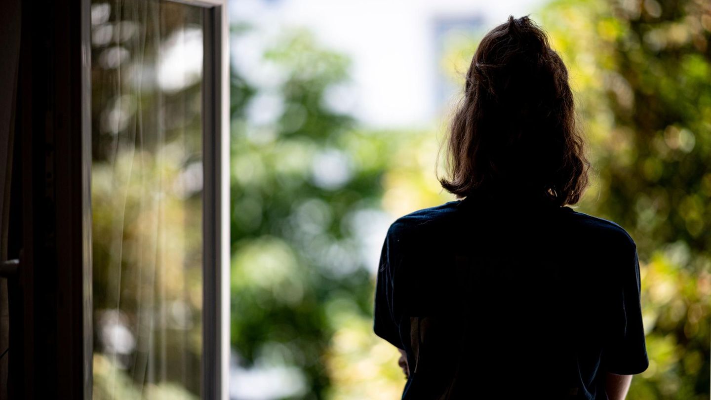 Eine Frau steht an einem offenen Fenster und schaut hinaus – Symbolbild Mutterschutz
