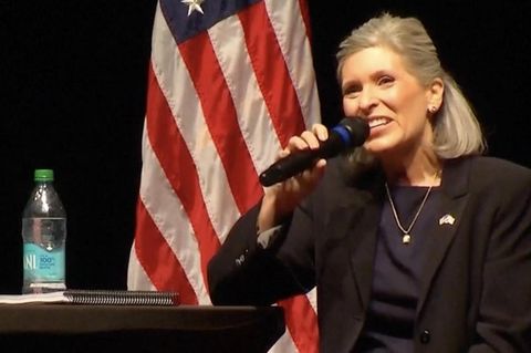 Joni Ernst sitzt auf einer Bühne bei einer Bürgerversammlung in Iowa und redet in ein Mikrofon