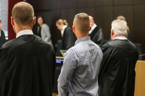 Ein Polizist (M) steht im Landgericht in Düsseldorf zwischen seinen Anwälten