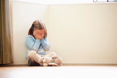 Kindesmissbrauch: Kleines Kind sitzt auf dem Boden und hält sich die Augen zu
