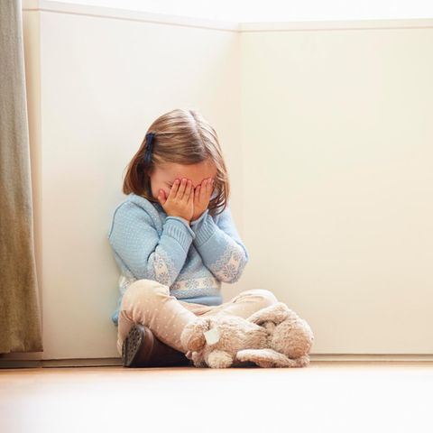 Kindesmissbrauch: Kleines Kind sitzt auf dem Boden und hält sich die Augen zu