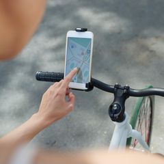 Frau, die die Navigator-Anwendung auf ihrem Telefon verwendet, wenn sie Fahrrad fährt