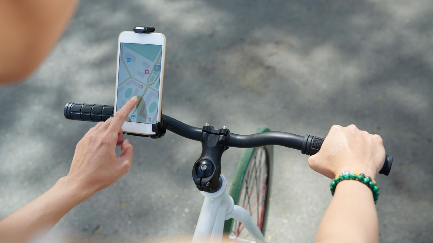 Frau, die die Navigator-Anwendung auf ihrem Telefon verwendet, wenn sie Fahrrad fährt