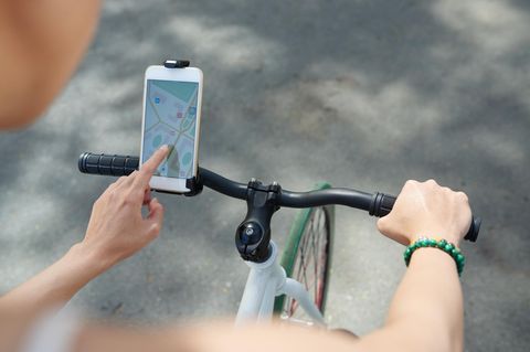 Frau, die die Navigator-Anwendung auf ihrem Telefon verwendet, wenn sie Fahrrad fährt
