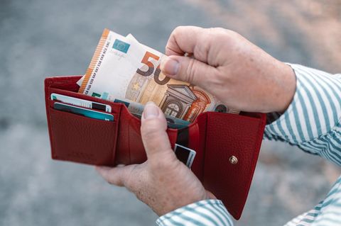 Ein Mann holt Bargeld aus seiner Geldbörse