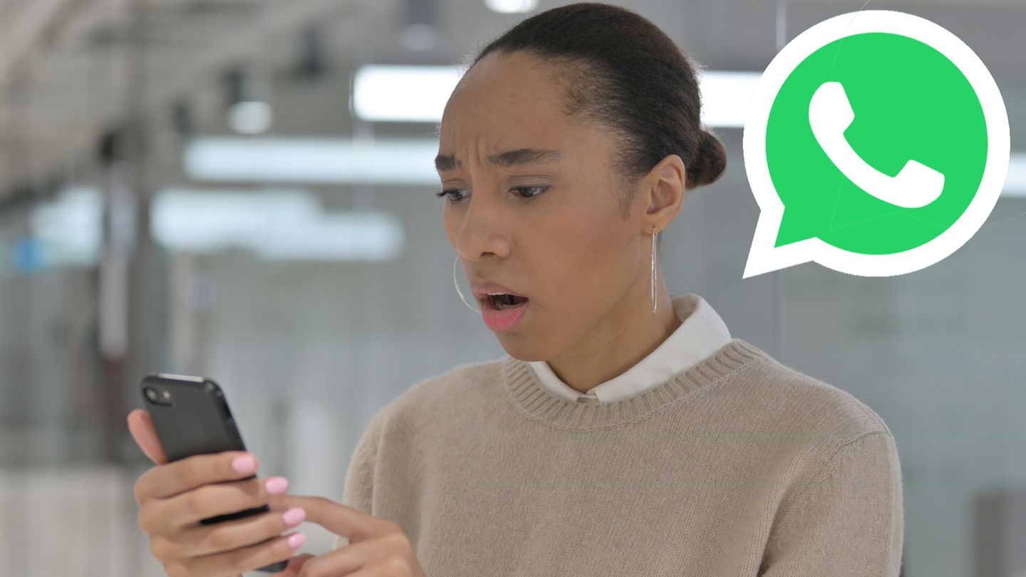 Eine Frau schaut erschrocken auf ihr smartphone. Oben rechts ist das Whatsapp-Logo zu sehen
