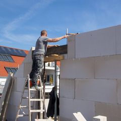 Ein Maurer arbeitet auf der Baustelle eines Einfamilienhauses