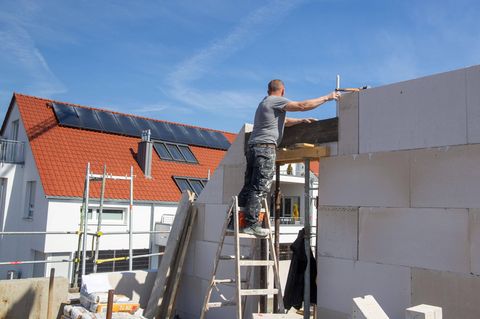 Ein Maurer arbeitet auf der Baustelle eines Einfamilienhauses