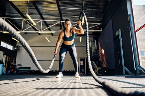 Hyrox Training: Athletin trainiert mit Battle Ropes