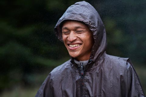 Ein Mann steht mit seiner Regenjacke im Regen