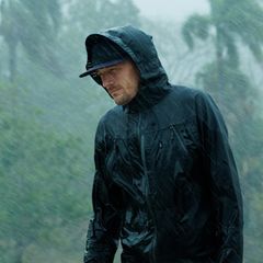 Ein Mann steht mit seiner Regenjacke im Regen