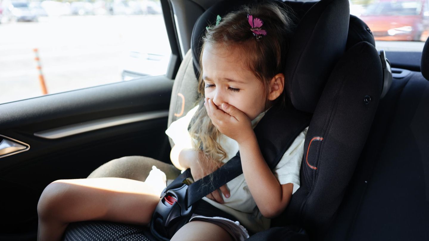 Kleines Mädchen im Auto hält sich die Hand vor den Mund