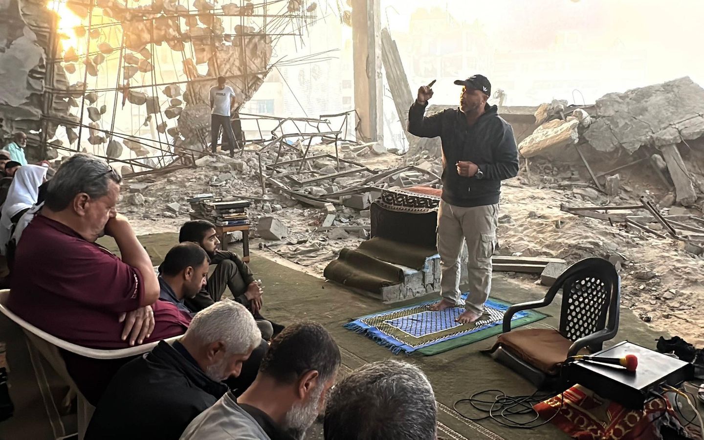 Viele Gläubige sitzen in den Ruinen einer Moschee