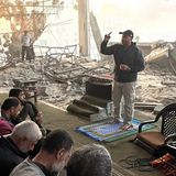 Viele Gläubige sitzen in den Ruinen einer Moschee