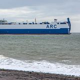 Ein Frachter mit der Aufschrift ARC auf dem Meer, nah an der Küste