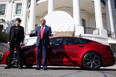 Elon Musk und Donald Trump stehen vor einem roten Tesla