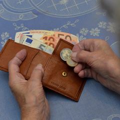 Eine Frau hält ein paar Geldstücke und ein Portemonnaie in der Hand
