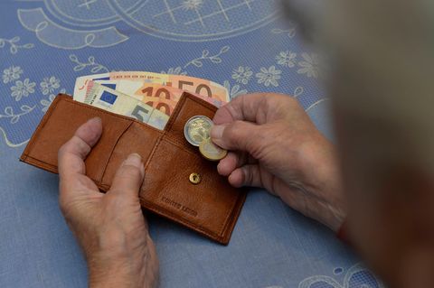 Eine Frau hält ein paar Geldstücke und ein Portemonnaie in der Hand