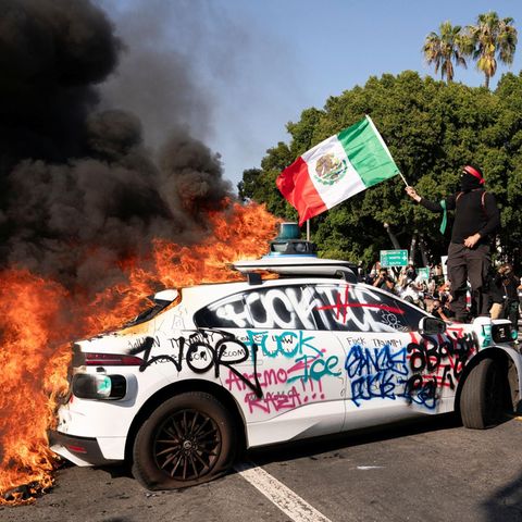 Los Angeles scenes: A hooded demonstrator stands with Mexico flag on the bonnet of a burning car on which "fuck ICE" was lubricated. ICE is the United States Immigration Authority, which carries out raids against illegal immigrants in a large area in the country on the instructions of Trump