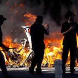 Im Stadtzentrum wurden immer wieder Autos angezündet. Hier passieren Demonstranten die verkohlten Reste mehrerer Fahrzeuge