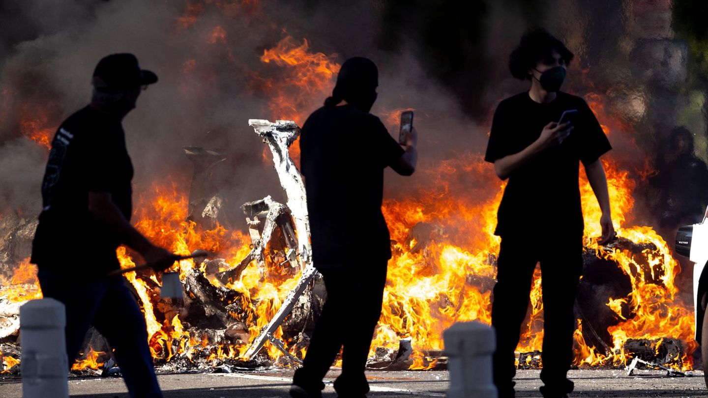 Im Stadtzentrum wurden immer wieder Autos angezündet. Hier passieren Demonstranten die verkohlten Reste mehrerer Fahrzeuge