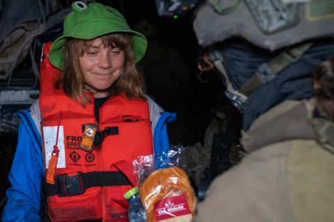 Ein Soldat überreicht Greta Thunberg ein Sandwich und eine Wasserflasche