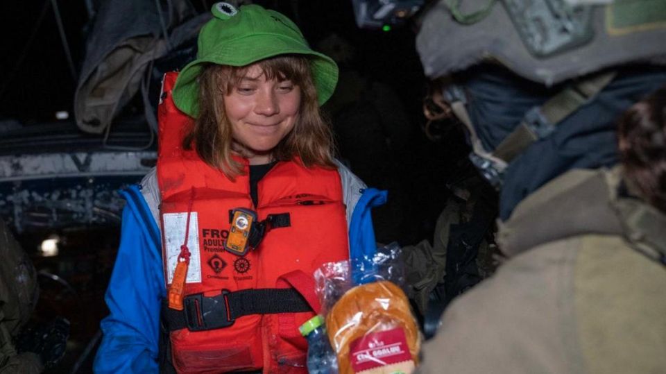 A soldier presents Greta Thunberg a sandwich and a water bottle