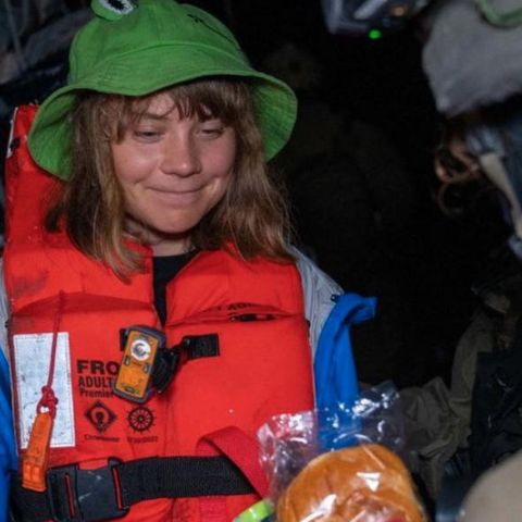 A soldier presents Greta Thunberg a sandwich and a water bottle