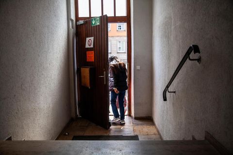 Eine Frau, sie ist ein Asylbewerber,  verlässt ein Treppenhaus und geht durch eine Tür