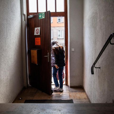 Eine Frau, sie ist ein Asylbewerber,  verlässt ein Treppenhaus und geht durch eine Tür
