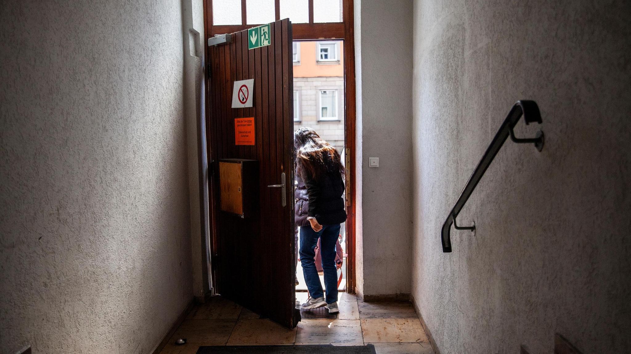 Eine Frau, sie ist ein Asylbewerber,  verlässt ein Treppenhaus und geht durch eine Tür