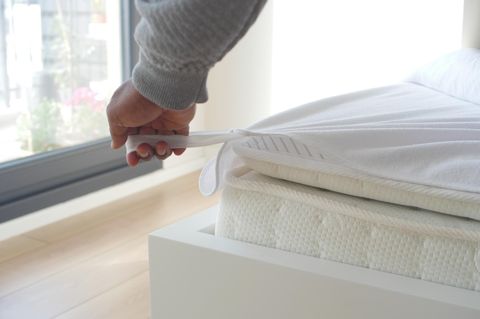 Jemand zieht einen Matratzenschoner über.