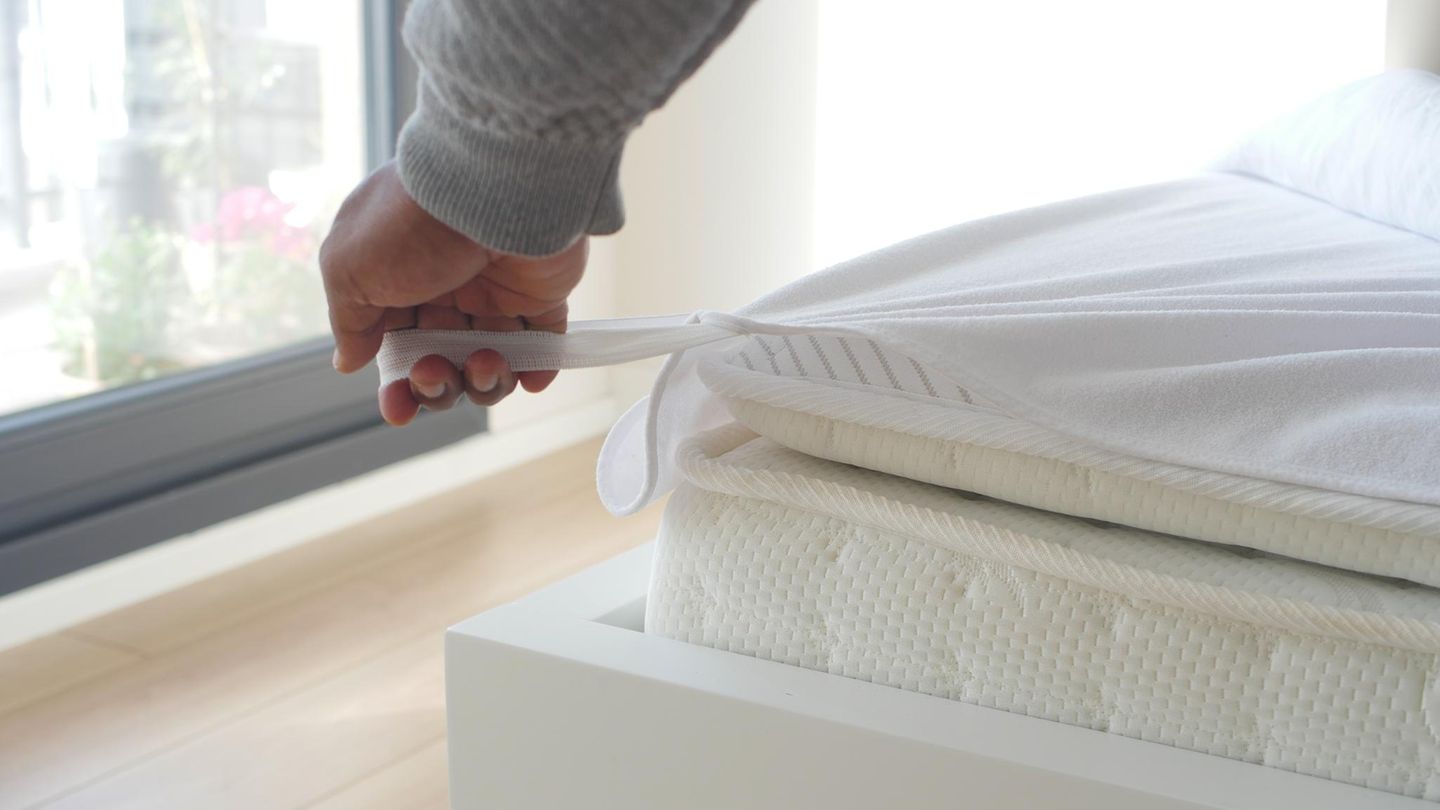 Jemand zieht einen Matratzenschoner über.