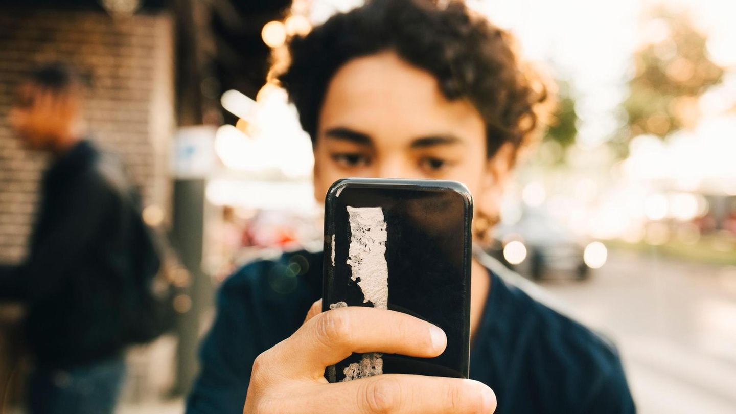 Junge mit Smartphone vor dem Gesicht: Bei der Erziehung von Jungs spielt es eine große Rolle