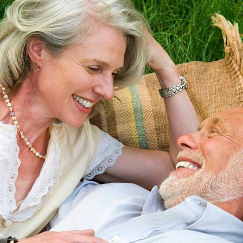Älteres Paar liegt auf einer Picknickdecke und spricht über Rente