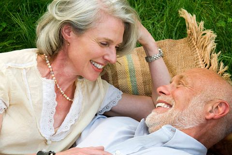 Älteres Paar liegt auf einer Picknickdecke und spricht über Rente