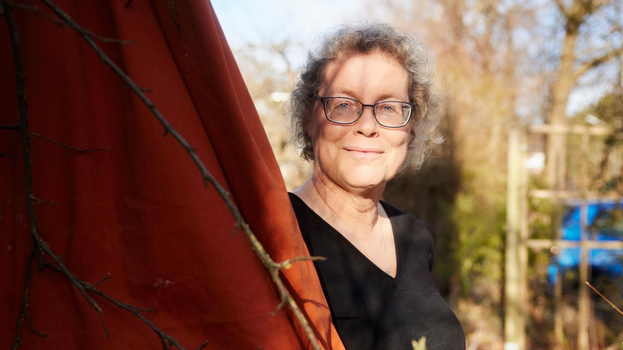 Katja Brandis steht vor einem roten Tuch in ihrem Garten