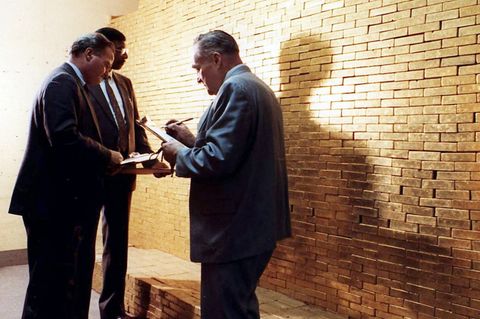 Angestellte der New York Federal Reserve Bank stehen vor einer Wand aus Goldbarren