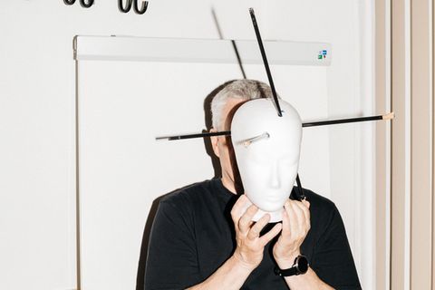Fred Zack hält sich ein Kopfmodell mit Markierungen von Pfeilverletzungen vors Gesicht