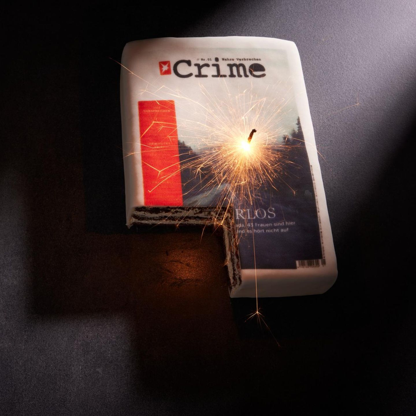 Ein Kuchen, auf den das Titelbild der ersten stern-Crime-Ausgabe gedruckt wurde, mit einer brennenden Wunderkerze