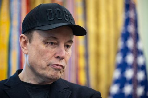 Elon Musk steht im Oval Office und schaut nachdenklich