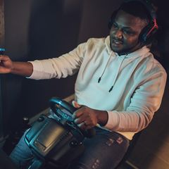 Ein Mann spielt mit seinem Sim-Racing-Lenkrad ein Rennspiel