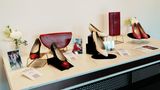 Ein Tisch mit drei Paar Schuhen, zwei Handtaschen, Fotos von Diana und Blumen