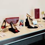 Ein Tisch mit drei Paar Schuhen, zwei Handtaschen, Fotos von Diana und Blumen