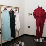 Roter Ski Anzug neben einer Klamottenstange mit weiteren Kleidern