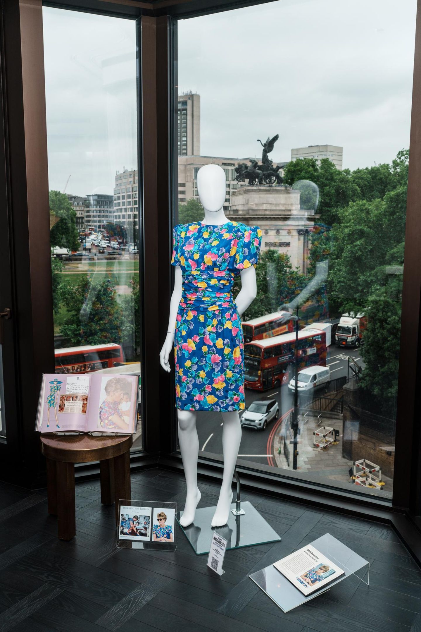 Eine Puppe trägt ein blumiges Kleid, dahinter zu sehen ist Londons Altstadt