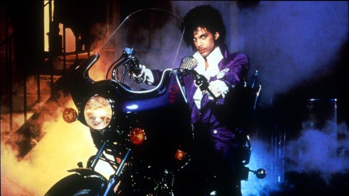 Prince im Film "Purple Rain" im lilafarbenen Anzug auf einer Harley Davidson