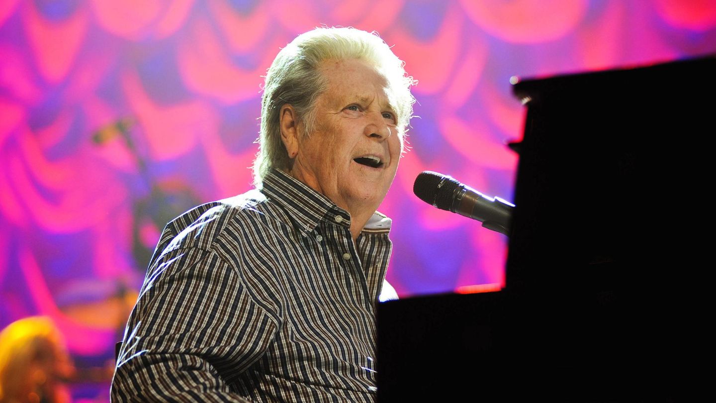 Brian Wilson sitzt am Klavier und singt in ein Mikrophon